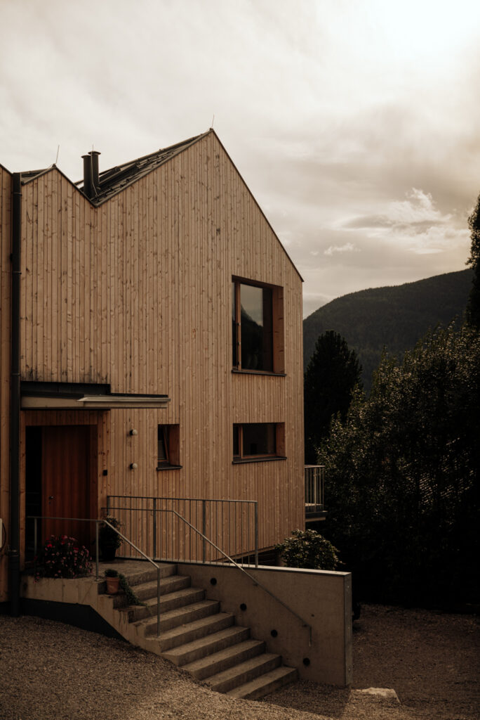 House with modern architecture with striking pitched roof, spruce wood façade and concrete entrance staircase