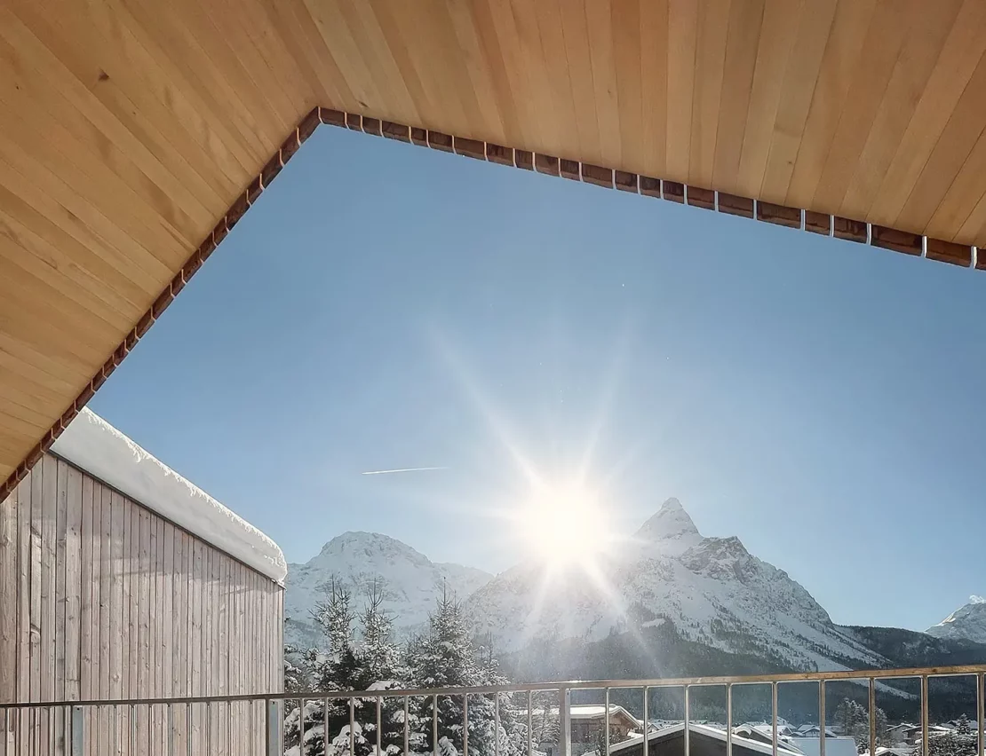 View of a striking mountain from a balcony of a house with a wooden façade