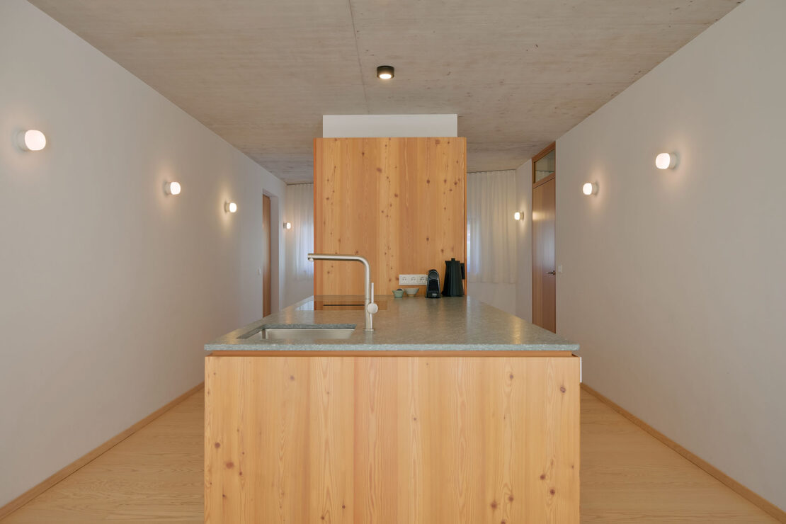 Carpenter-built cooking island with stone worktop in Apartment 1000 in Haus Aerli, designer lamps on the wall