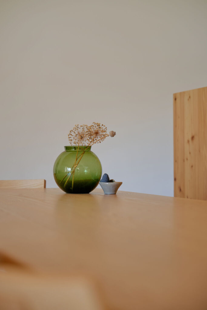Green transparent vase standing on a wooden table in the Aerli holiday house