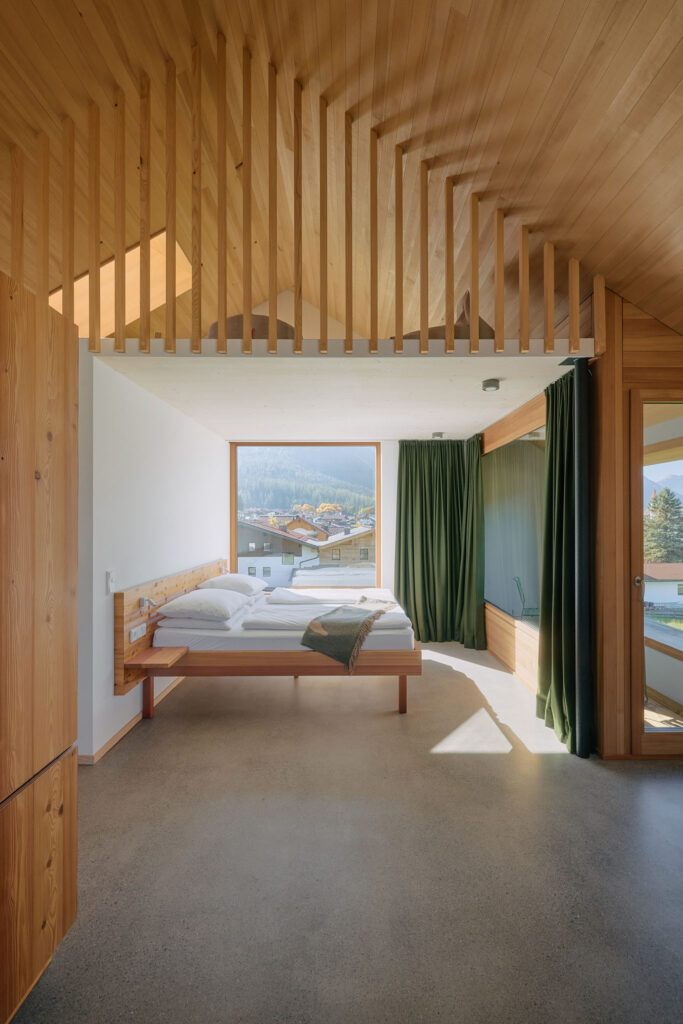 Apartment 1003 in the Aerli designer holiday home with open sleeping area with panoramic windows, above it a gallery under the exposed roof truss with wooden slats
