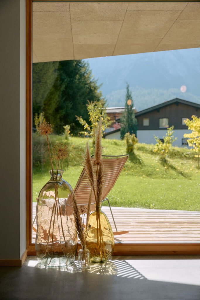 Blick durch bodentiefe Fensterfront aus Schaukelstuhl und Garten des Haus Aerli
